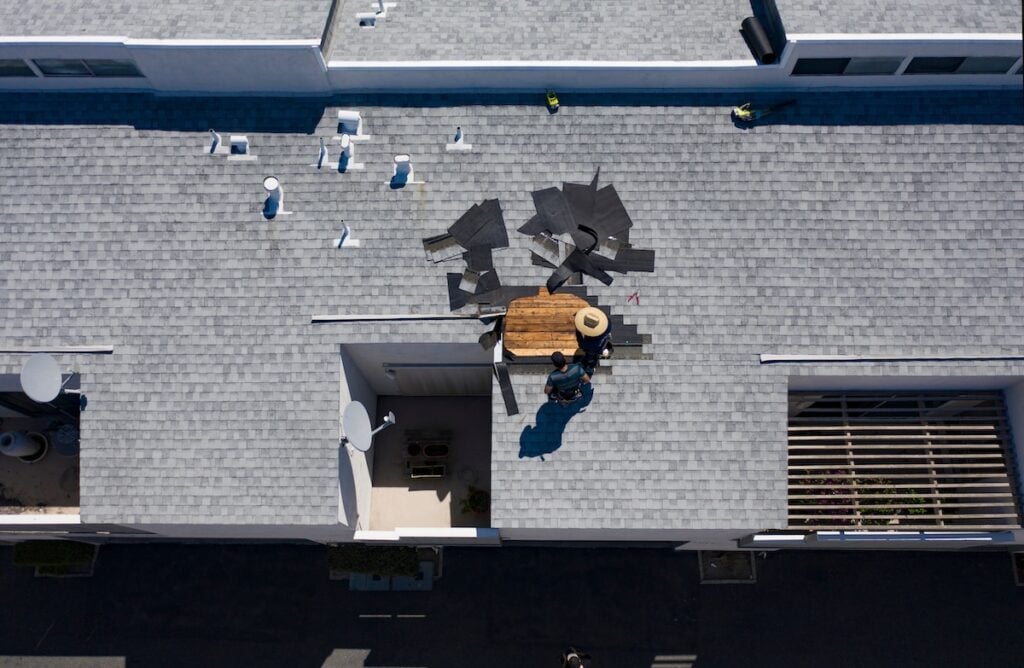 garner nc commercial From a bird's-eye view, a person in a hat diligently works on a shingled gray roof in Lake Forest. Scattered shingles hint at repairs near the house's square opening and adjacent lattice structure.