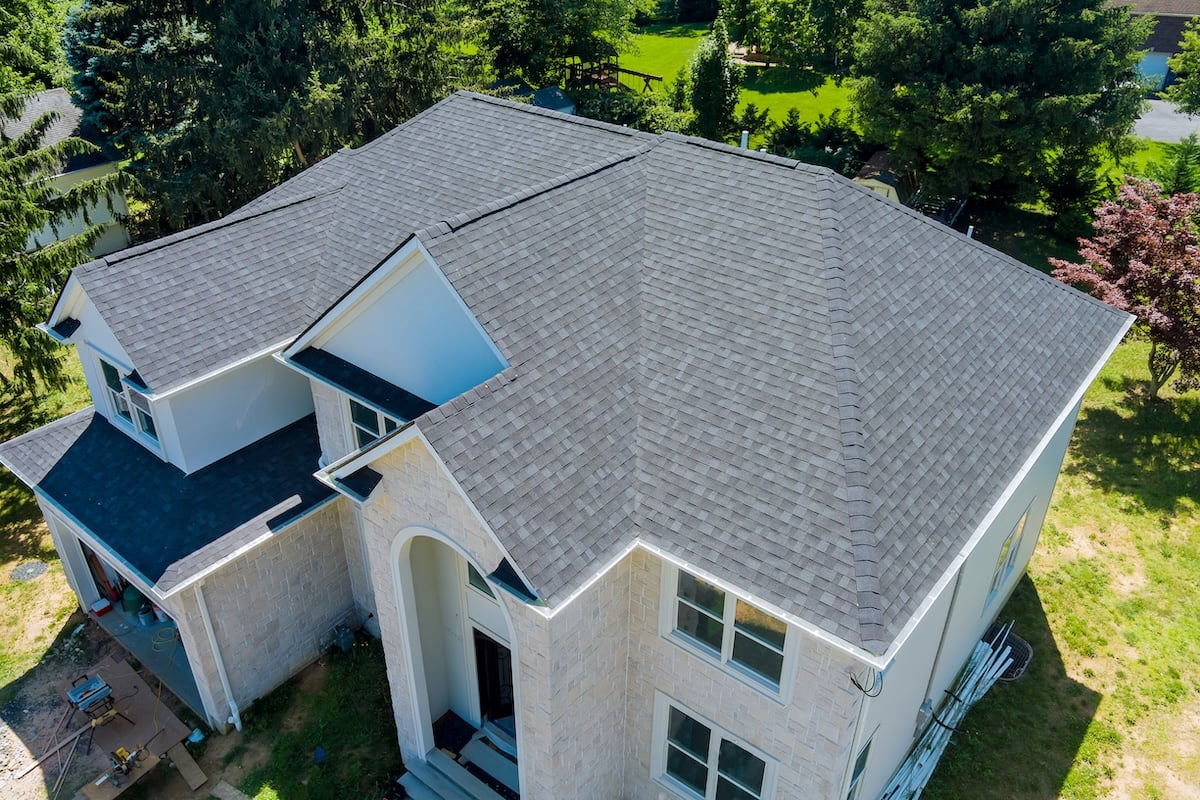 Aerial view of a large house with a gray shingle roof
