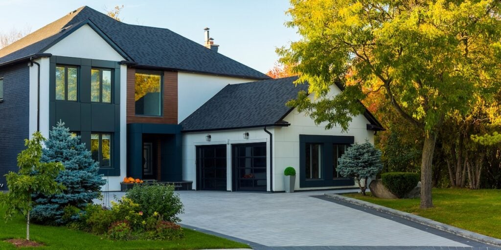Modern two-story house with gray and white facade, with modern black asphalt roof shingles