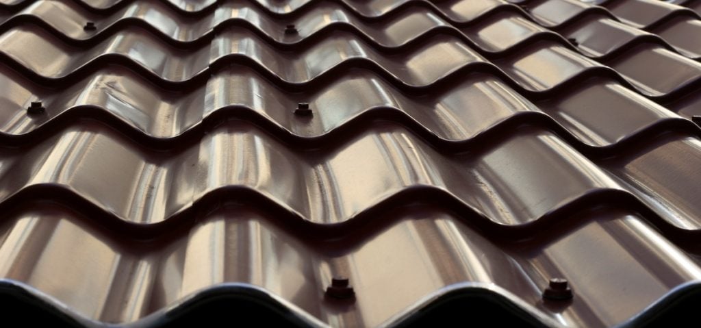 Close-up of wavy, dark brown metal roof panels with bolts fastening them in place