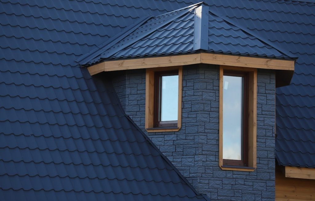 Close-up of a modern house roof with dark blue metal tiles treated with metal roof coating