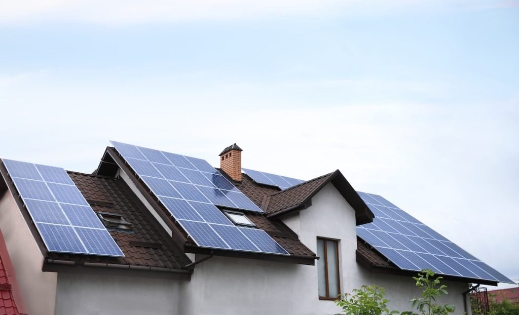 A modern house with multiple solar panels installed as part of recent roof upgrades