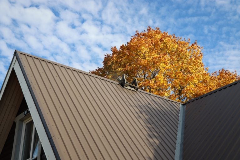 A brown metal roof of a house with a rooftop vent
