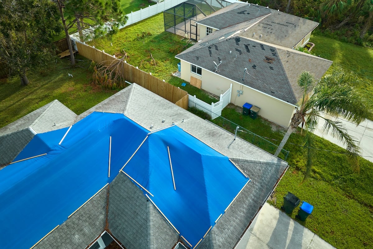 Aerial view of a house with an emergency roof tarp covering part of the roof