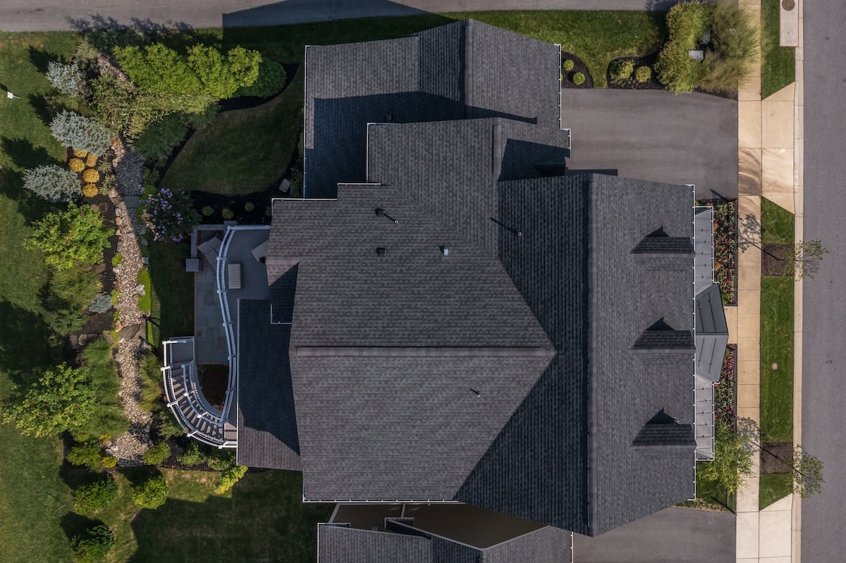 Aerial view of a large house with black shingles on the roof