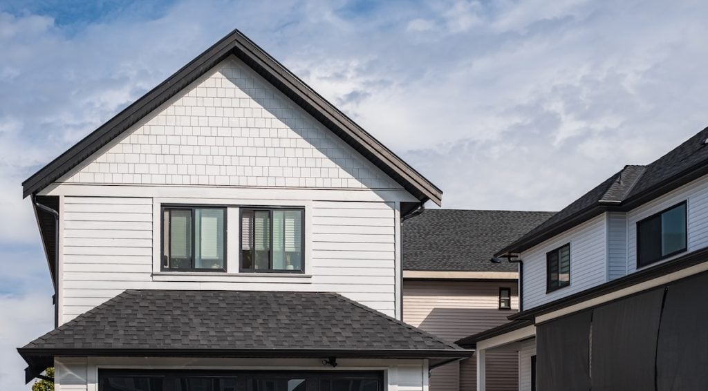 Modern two-story house with white siding, black shingles on the roof