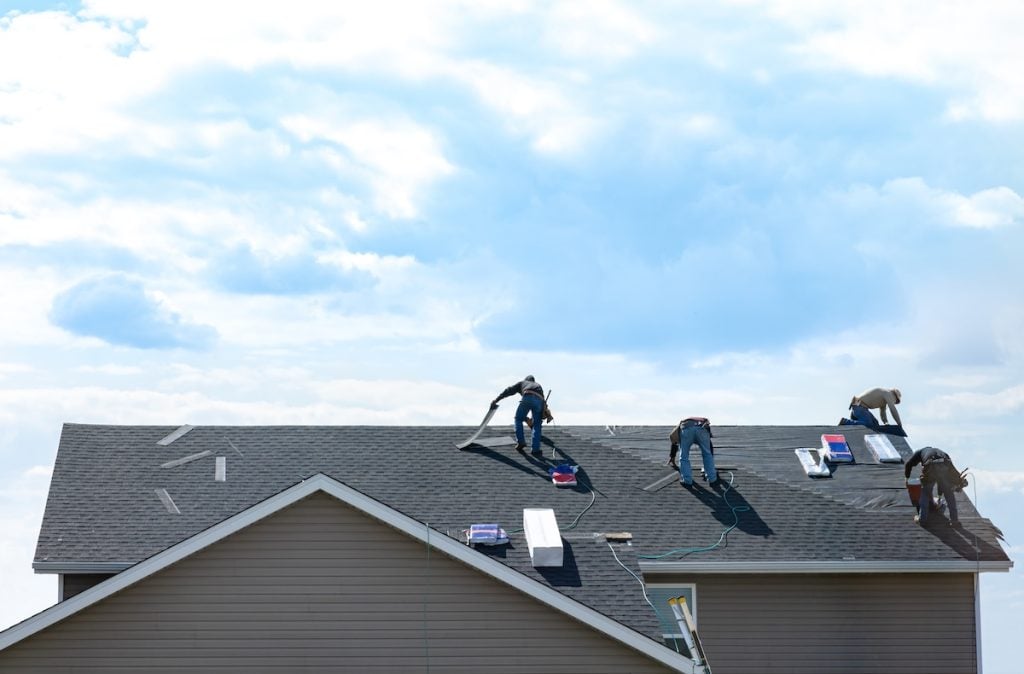 4 construction workers fixing roof