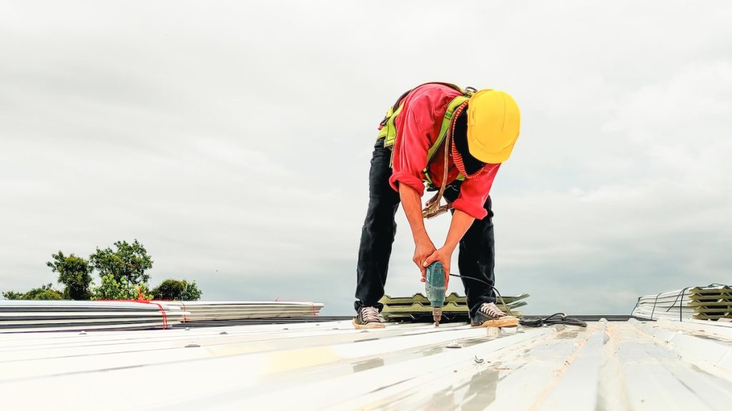 Construction worker install roof, Roofing tools, worke using Electric drill  replacement install roof roof plates.