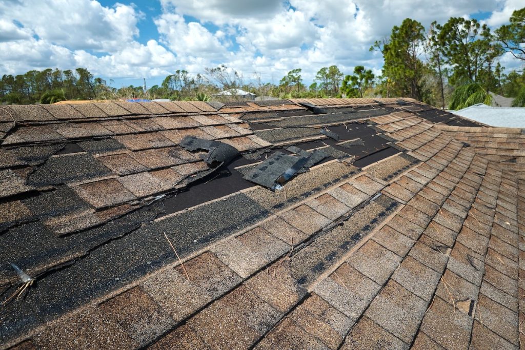 Damaged house roof with missing shingles 