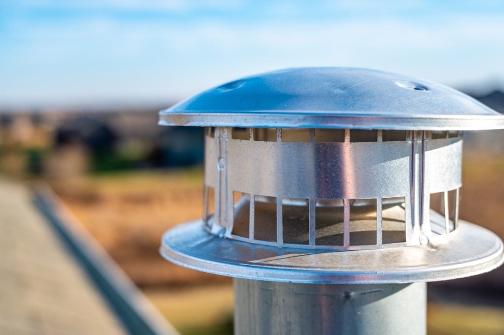 Typical rooftop chimney with a rain cap and shielding