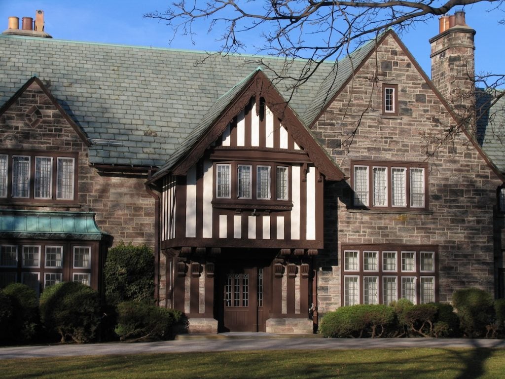 A large stone Tudor-style house with a steep slate roof