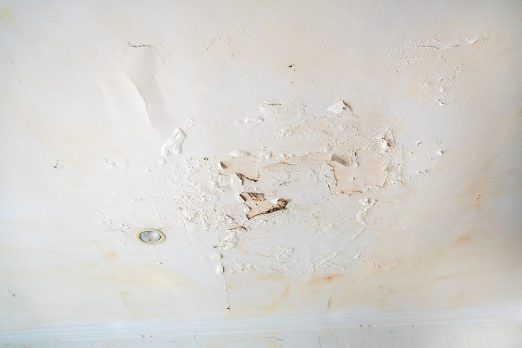 Rain water leaks on the wall causing damage and peeling paint next to some light bulbs