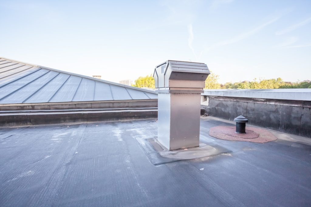 A flat rooftop features large metal flat roof ventilation in the center