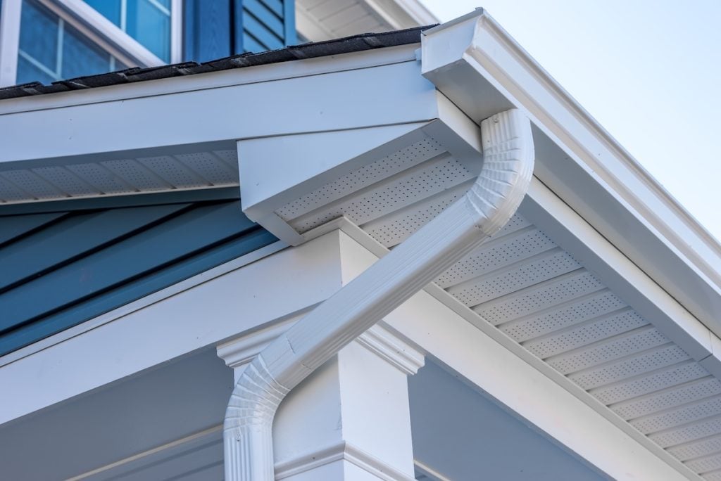 Close-up of a house’s corner showing white fascia, soffit, and rain gutter system
