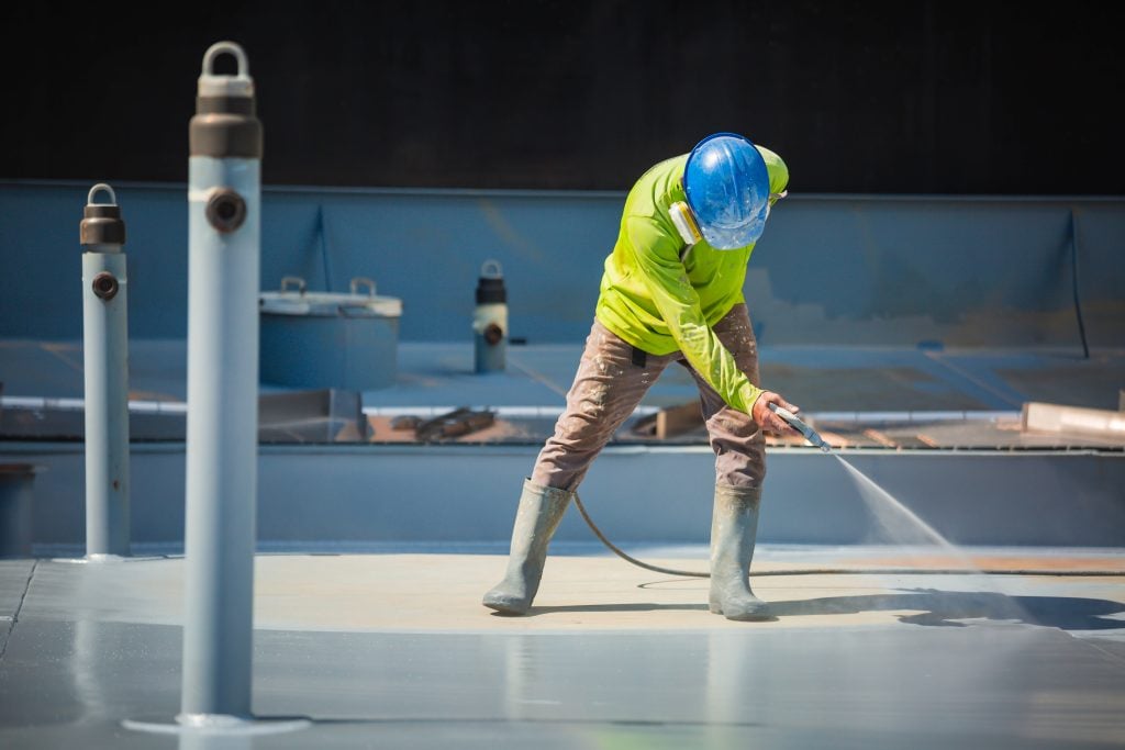 worker applying coating for a commercial roof