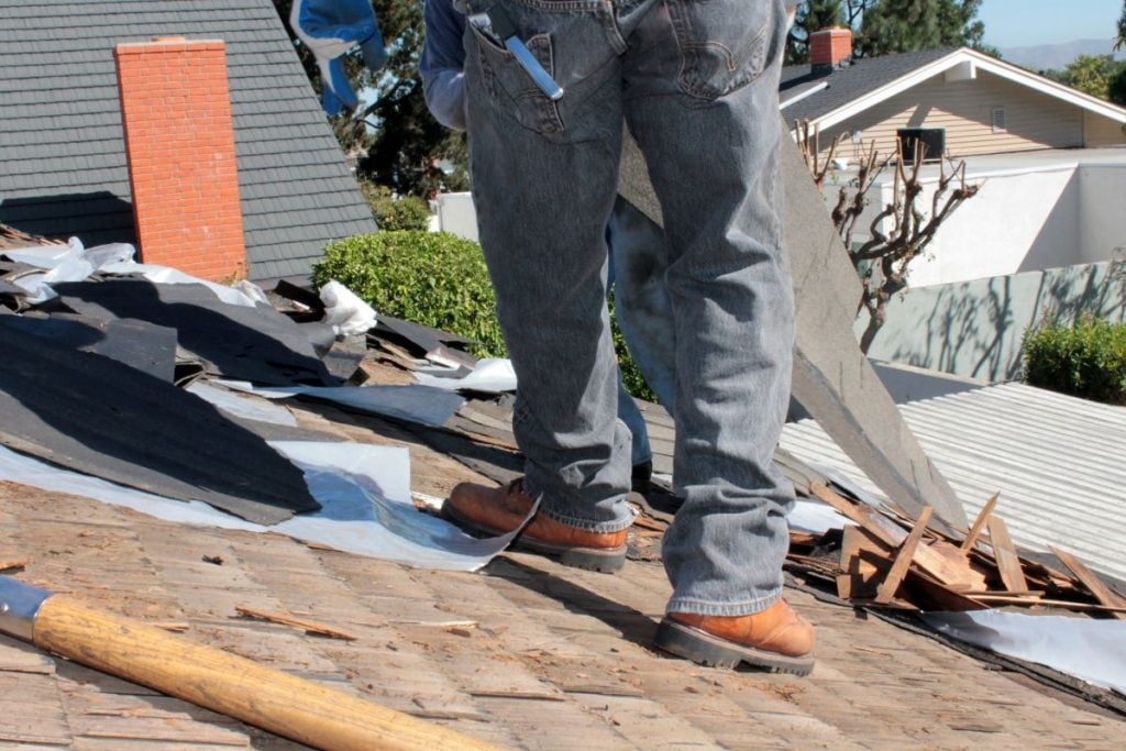 cedar shake roof maintenance worker inspecting fallen tiles