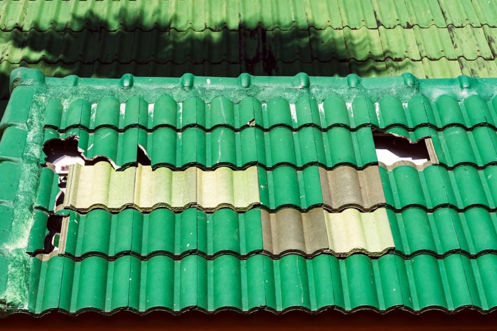 ght and dar green cracked shingles roof with holes destroyed after storm