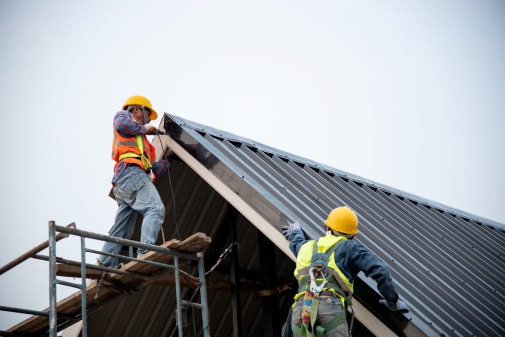 metal roof flashing two workers using safety helmet fixing blue metallic roof using tool