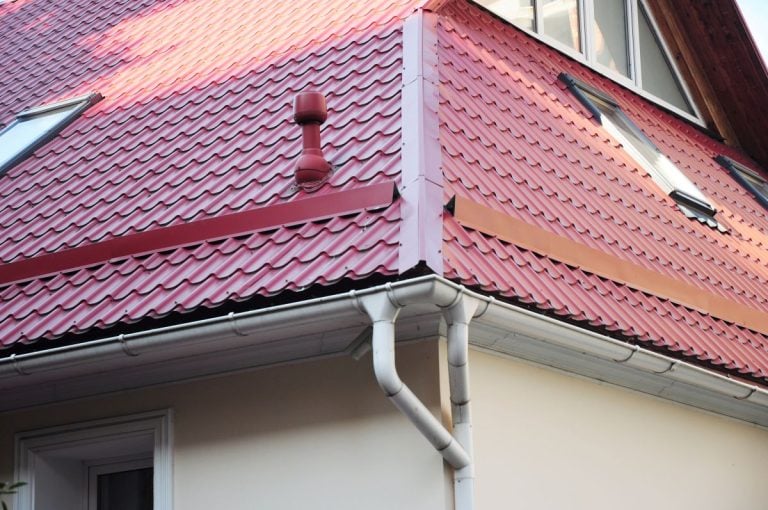 red metal roof flashing big house cream wall white windows pipe