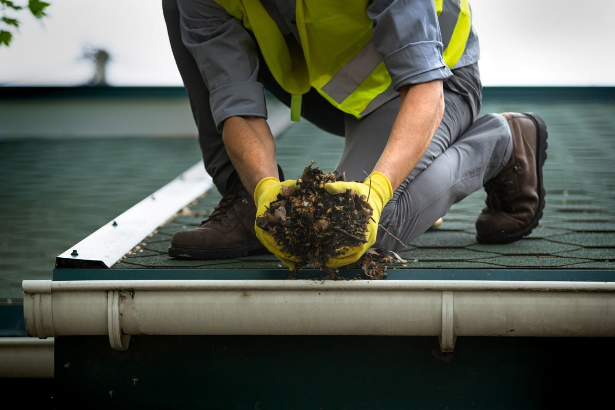 roof debris removal worker using hands to clean debris and leaves