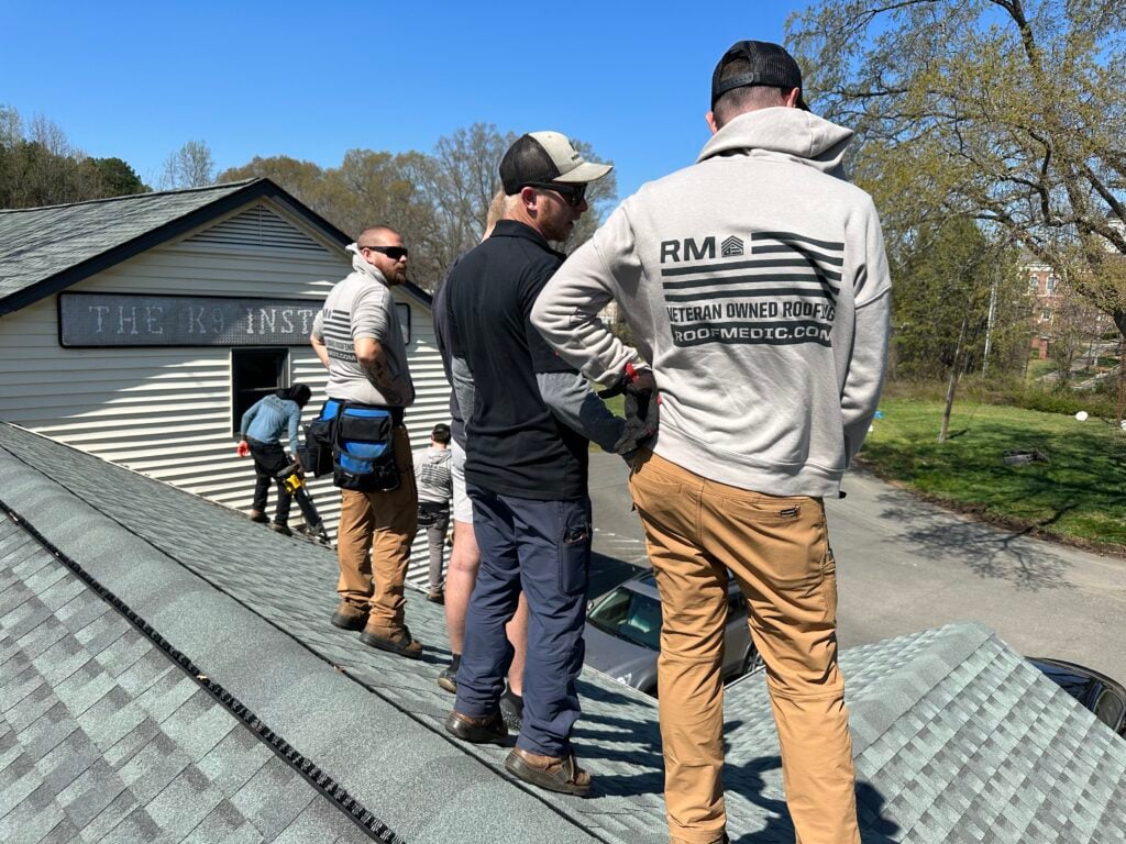 roof replacement cost charlotte nc workers standing on top of shingles roof