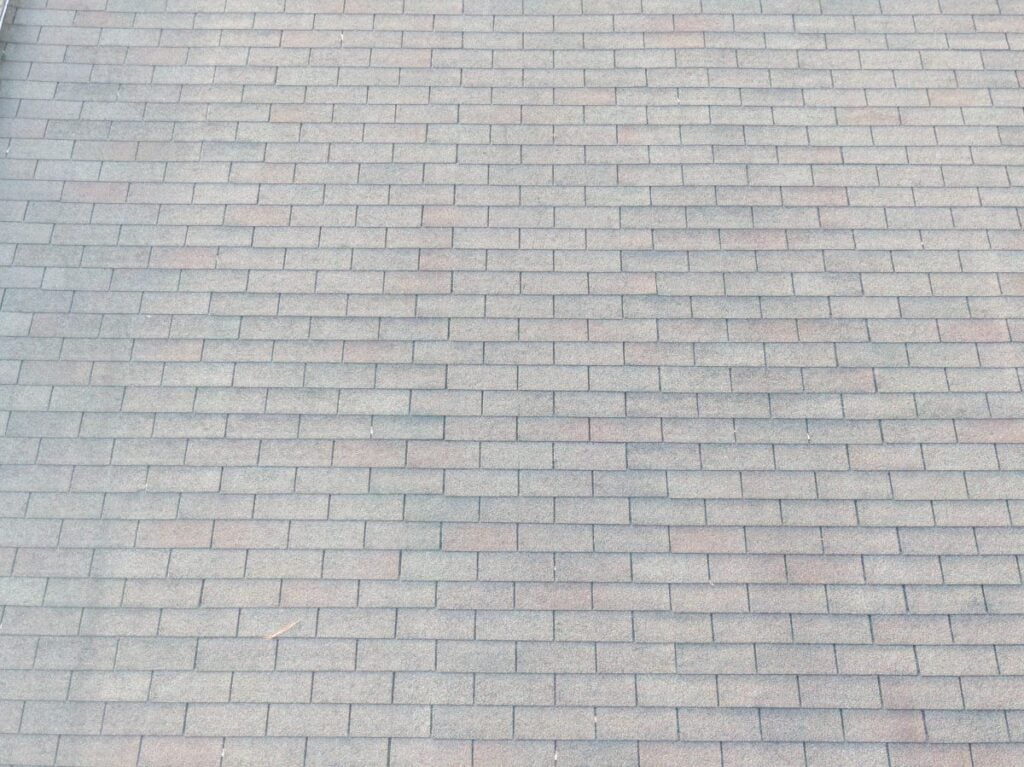 A close-up view of a rooftop with gray asphalt shingles arranged in a neat, overlapping pattern.
