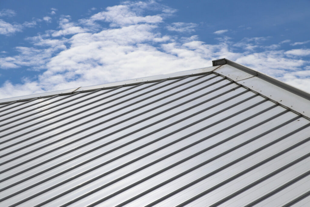 A metal roof against a blue sky with scattered clouds.